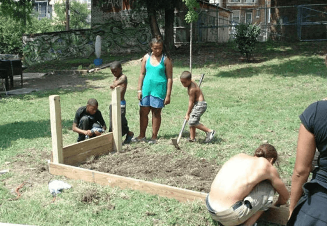 kids and adults are working in a garden