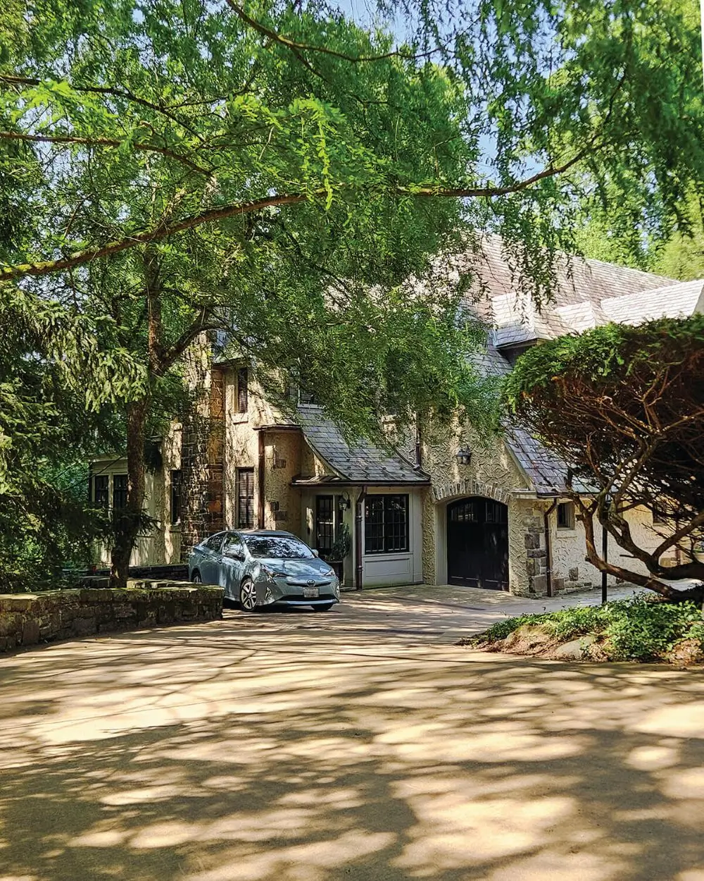 A charming stone house, partially shaded by lush green trees